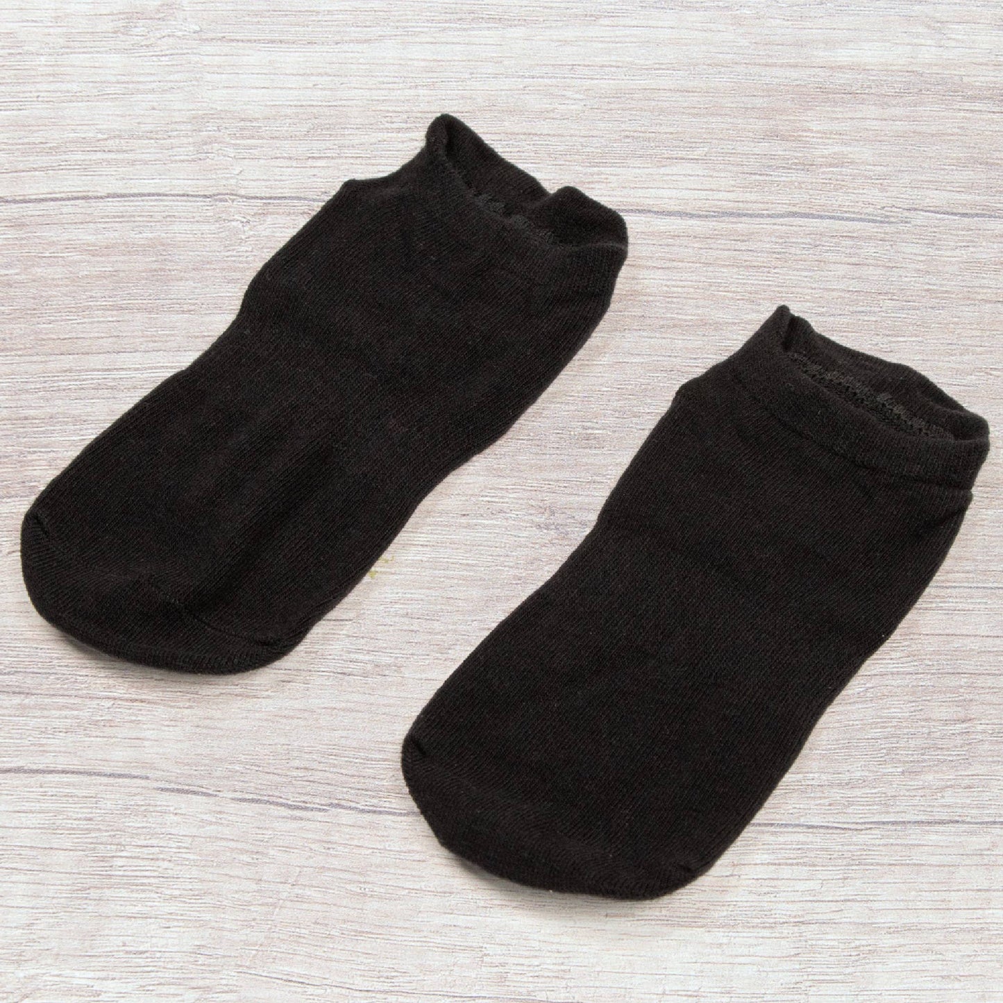 myga Yoga Socken Schwarz auf hellem Untergrund liegend.
