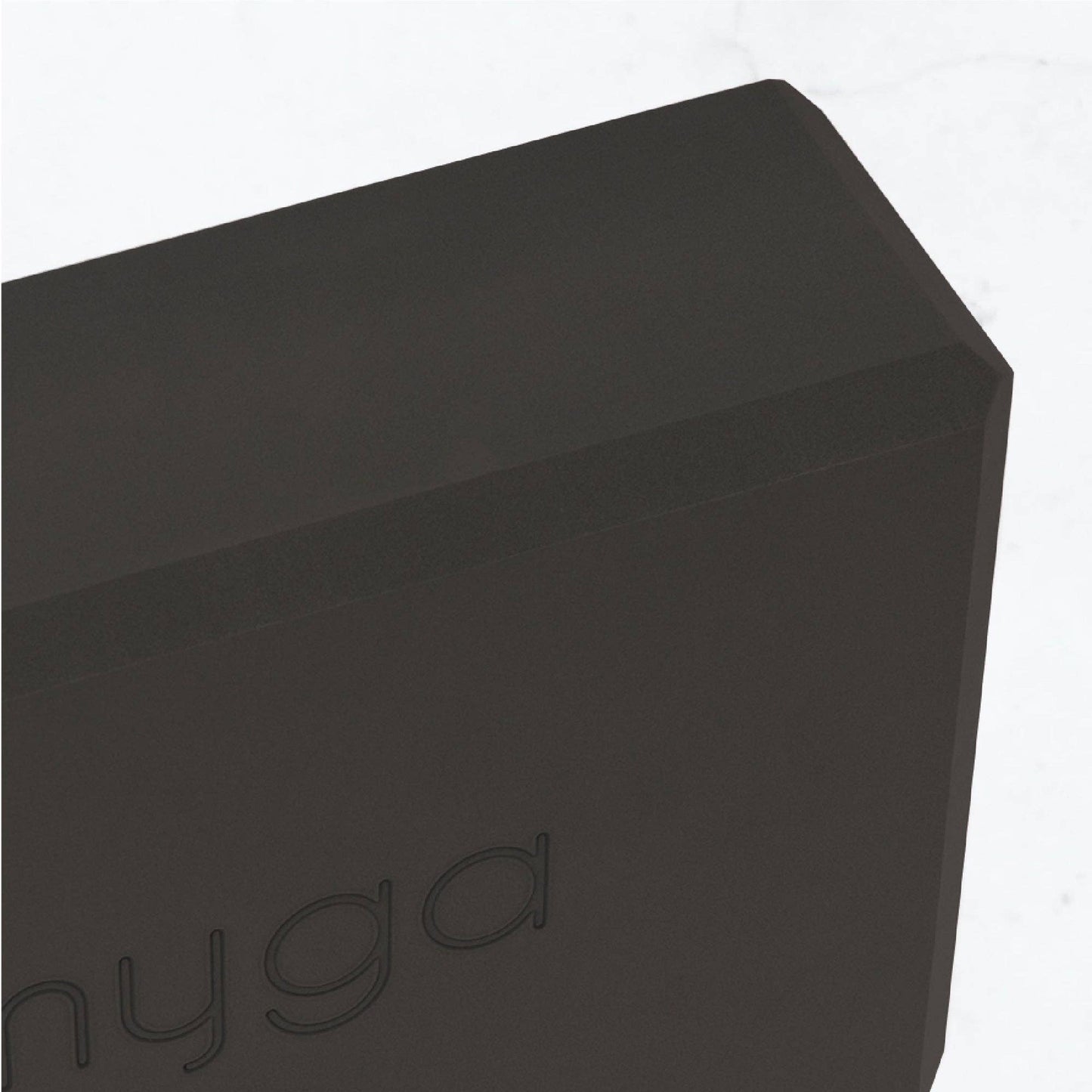Detailaufnahme der Ecke eines schwarzen Yogablocks von Myga. Sichtbares Logo und strukturierte, robuste Materialoberfläche.