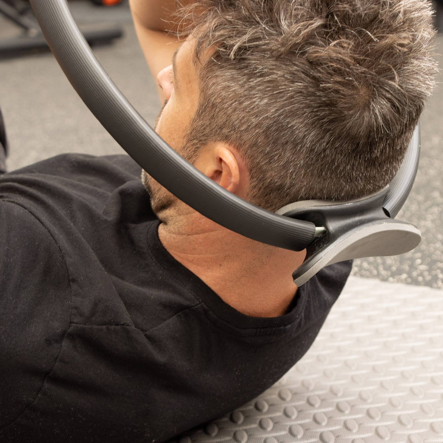 Mann verwendet den Pilatesring für Nacken- und Oberkörperübungen.