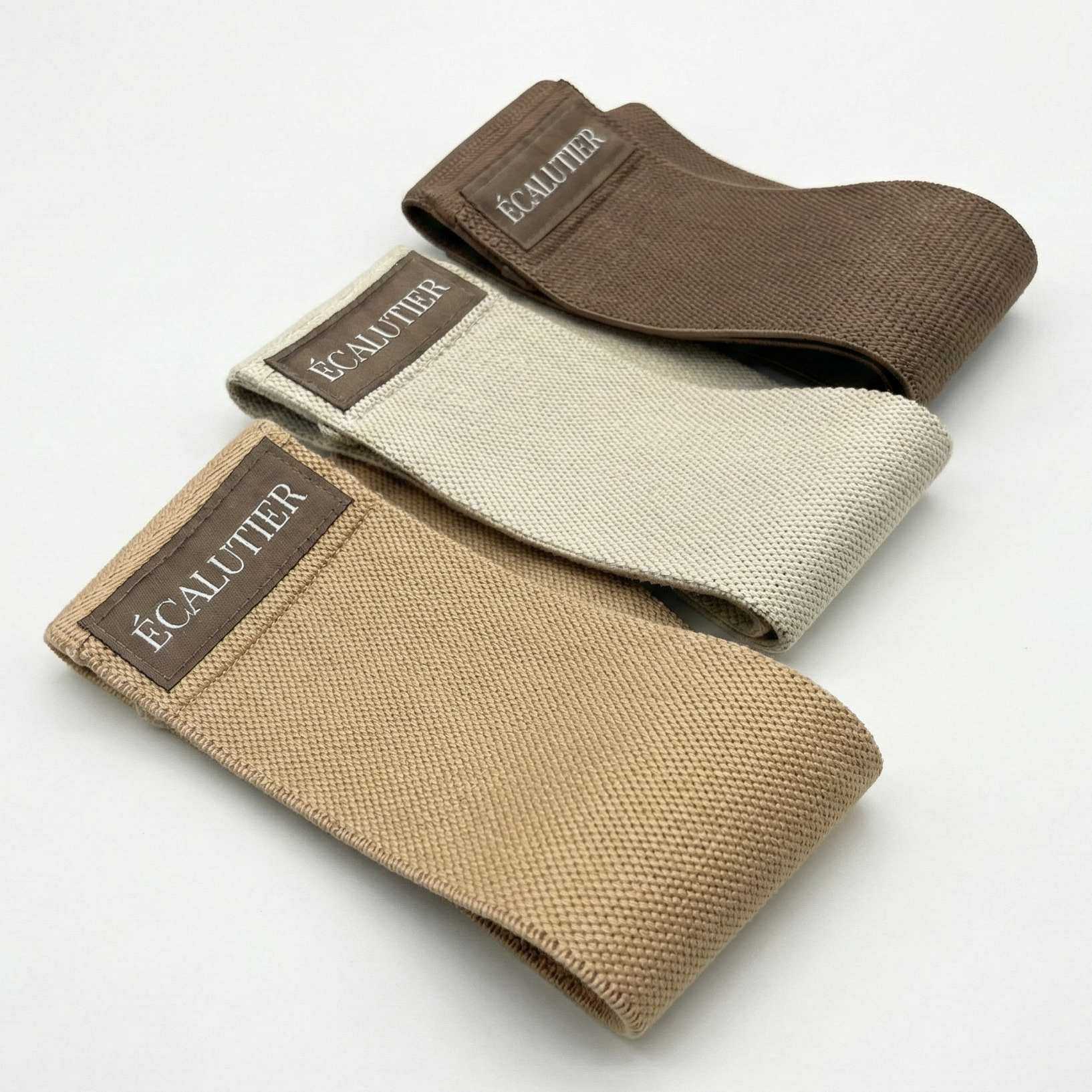 Drei Pilates Widerstandsbänder aus Stoff in Beige und Braun für das Training