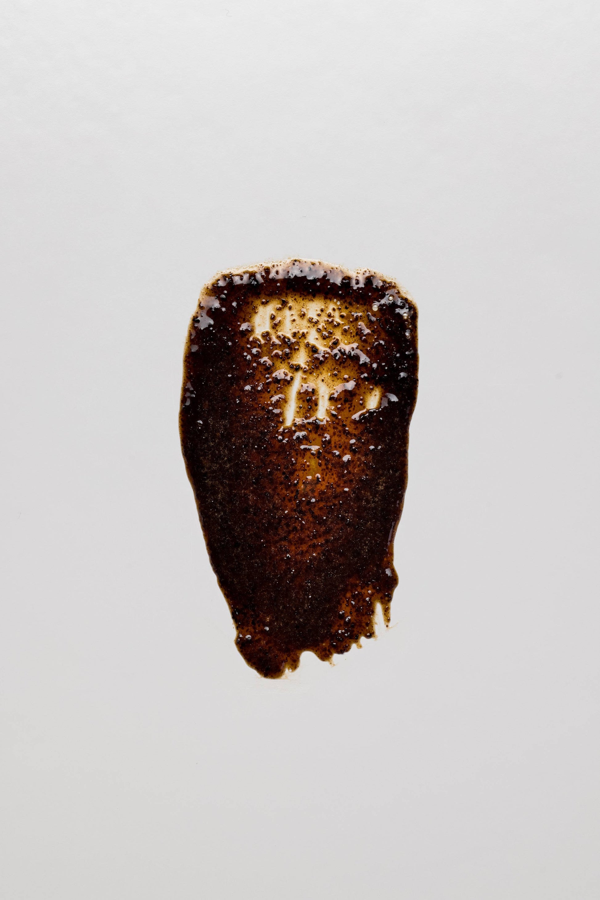 Textur des grums Raw Espresso Face Scrub + Mask auf weißem Hintergrund. Dunkle Peelingpaste aus recyceltem Kaffeesatz.