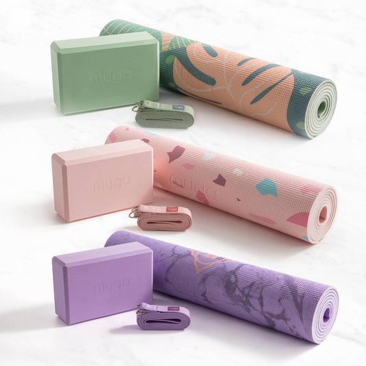 Drei bunte Yoga-Sets von Myga in Grün, Rosa und Lila – bestehend aus Yogamatte, Yogablock und Gurt – ordentlich nebeneinander auf einem hellen Hintergrund präsentiert.