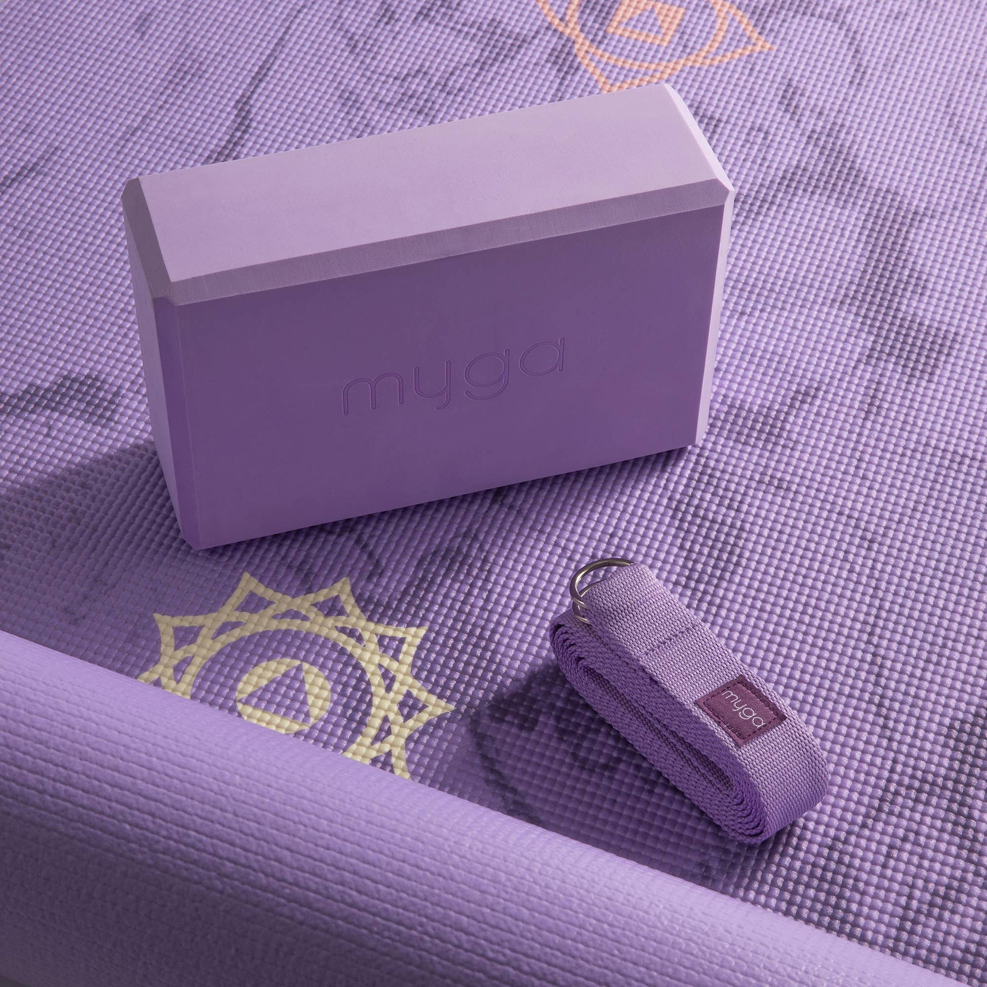 Lila Yoga-Set von Myga mit Yogamatte, Yogablock und Gurt – Nahaufnahme mit Mandala-Motiv auf der Matte.