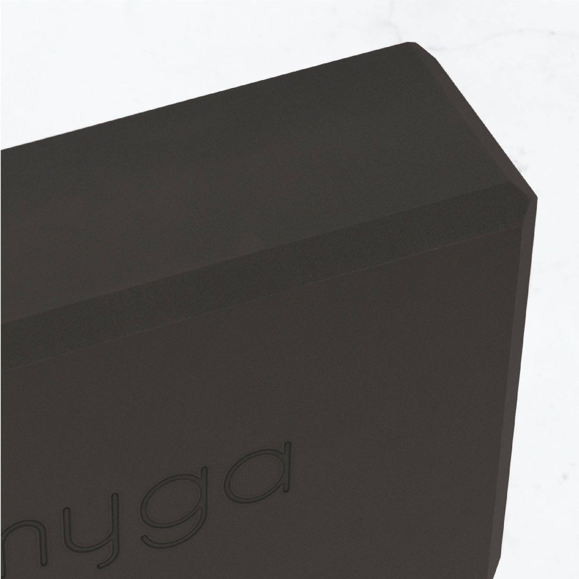 Detailaufnahme der Ecke eines schwarzen Yogablocks von Myga. Sichtbares Logo und strukturierte, robuste Materialoberfläche.