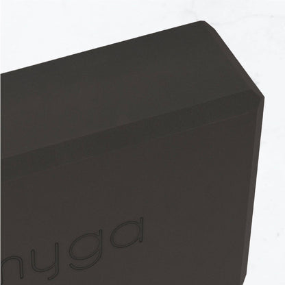 Detailaufnahme der Ecke eines schwarzen Yogablocks von Myga. Sichtbares Logo und strukturierte, robuste Materialoberfläche.